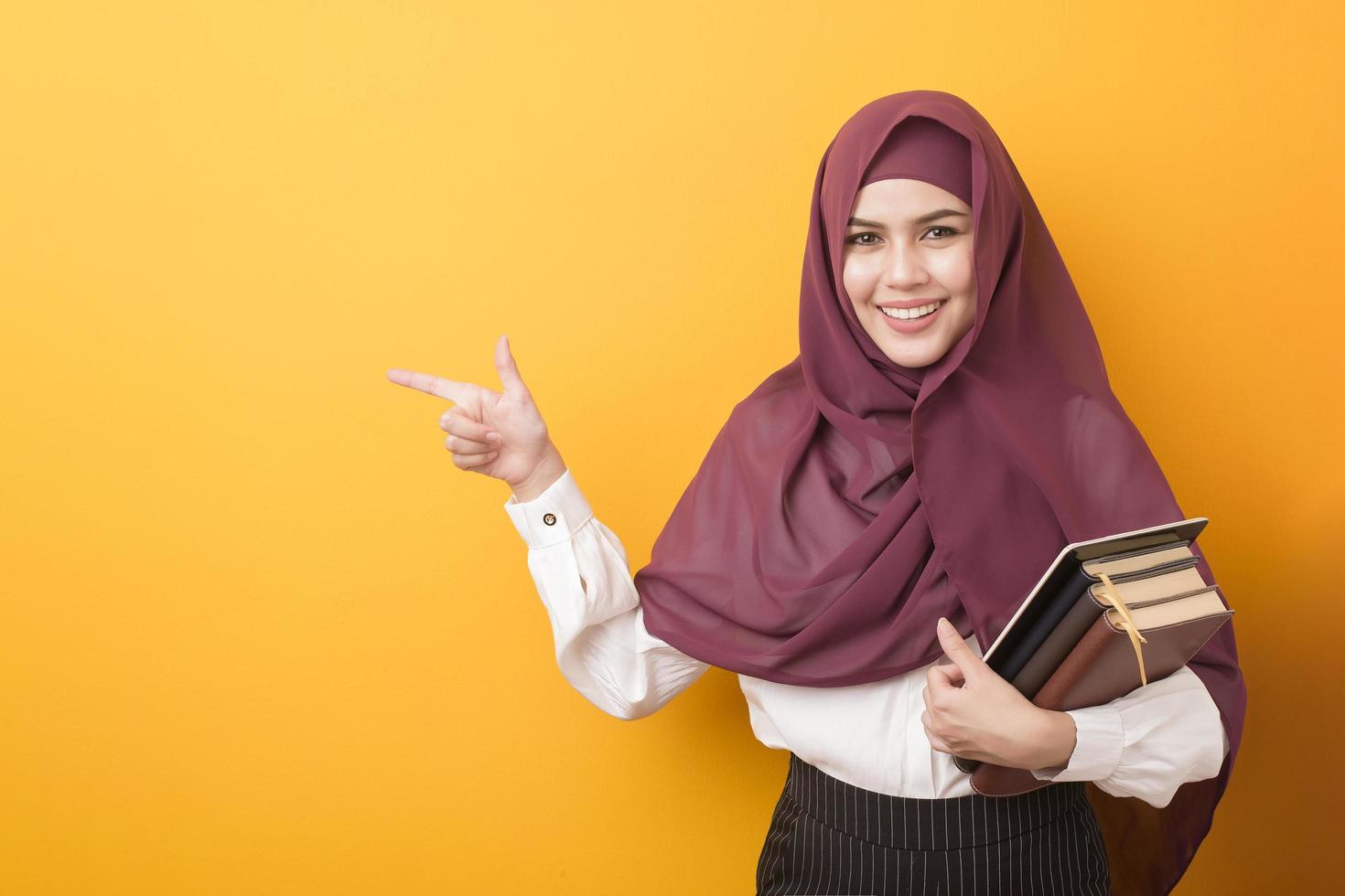 hermoso estudiante universitario con retrato de hiyab sobre fondo amarillo foto