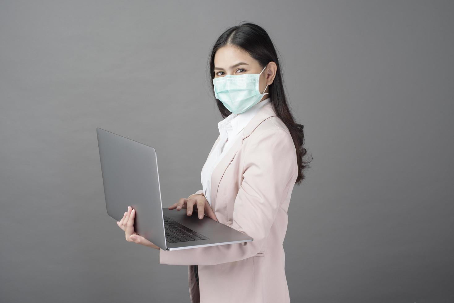 business woman with surgical mask is holding laptop computer photo