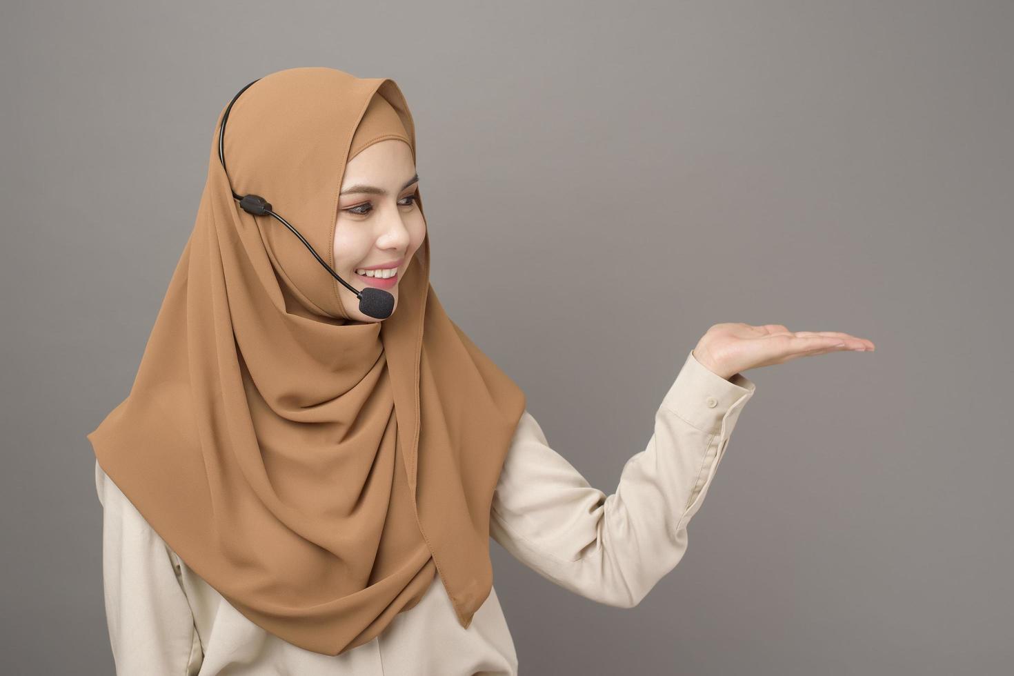 retrato de una hermosa mujer del centro de llamadas con hiyab sobre fondo gris foto