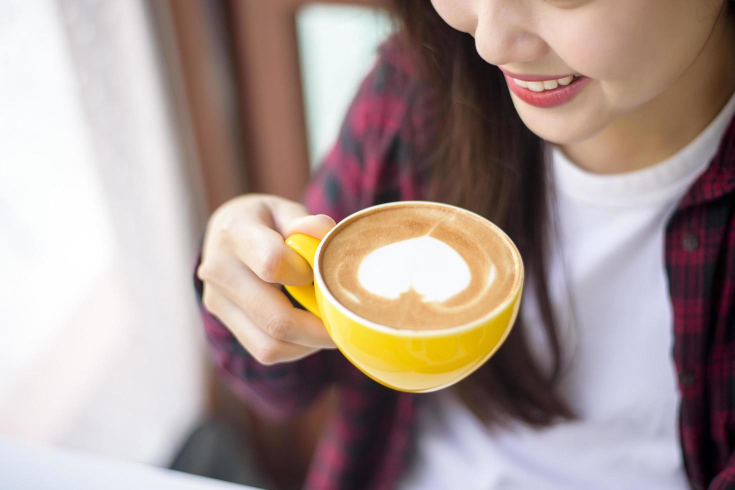 hot latte art in yellow cup on working desk photo