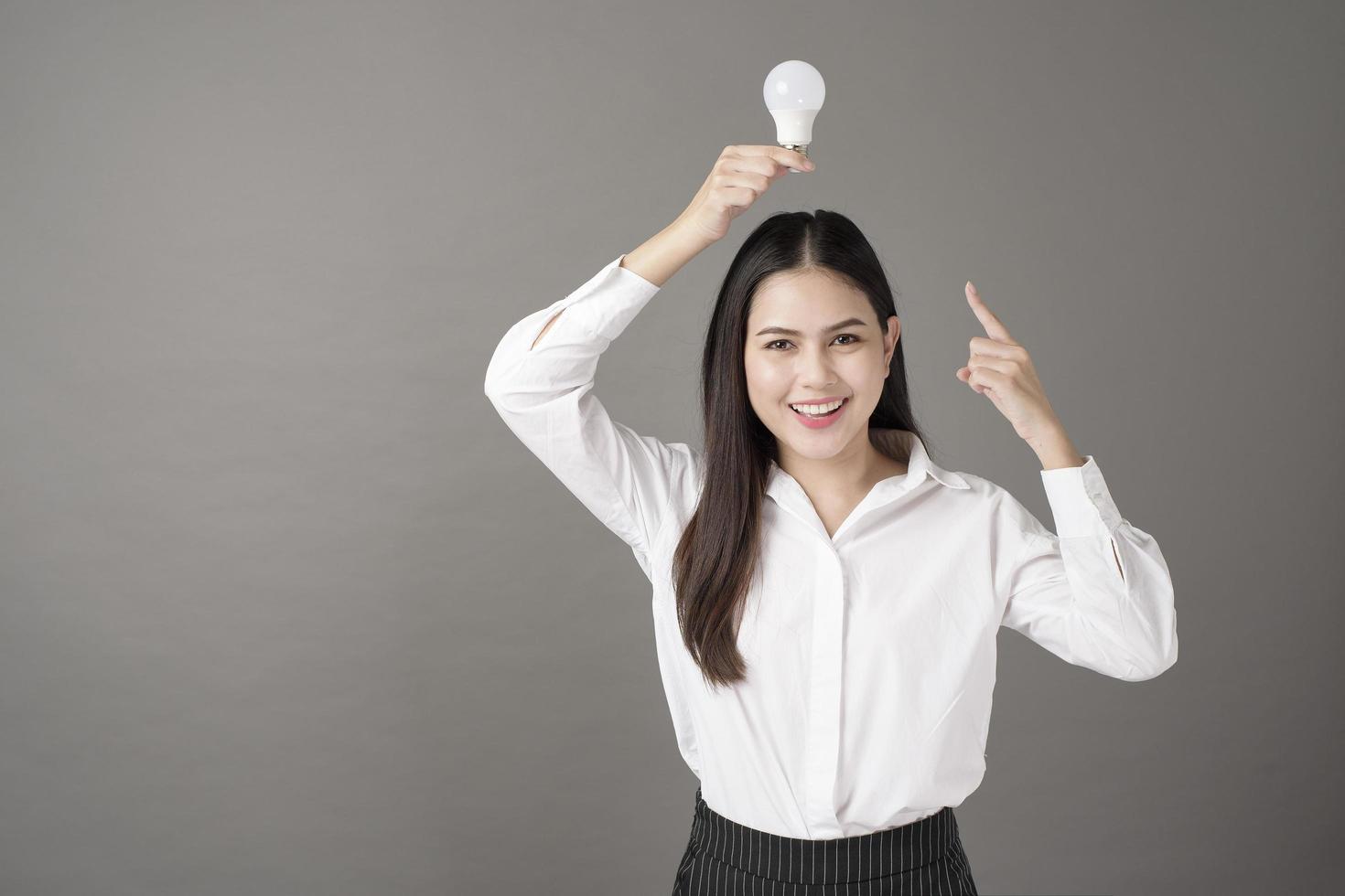Beautiful intelligent woman is holding light bulb in studio photo