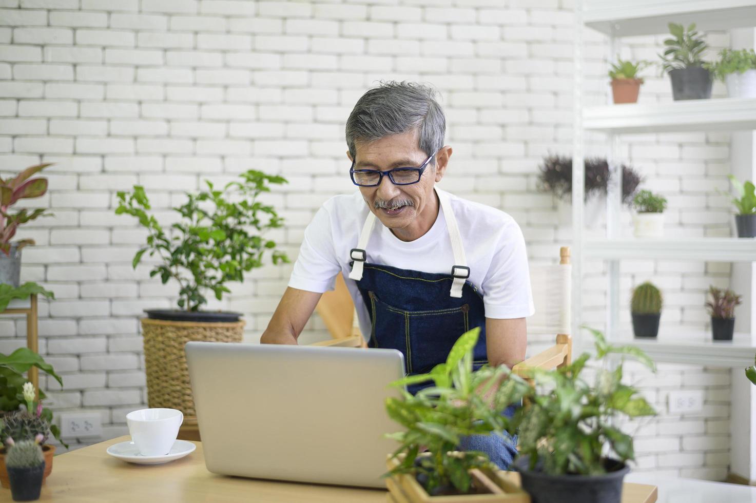 happy senior asian retired man with laptop  is relaxing  and enjoying  leisure activity in garden at home. photo