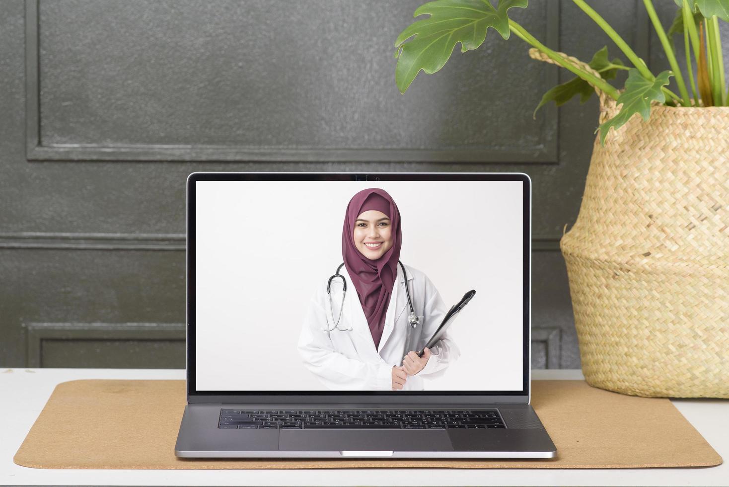 Female Muslim doctor making video call on social network with patient consulting about health problems. photo