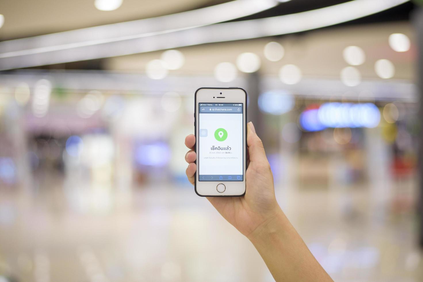 la mano de la gente sostiene un teléfono inteligente con la campaña thaichana de tailandia para la prevención de covid-19 en el centro comercial foto