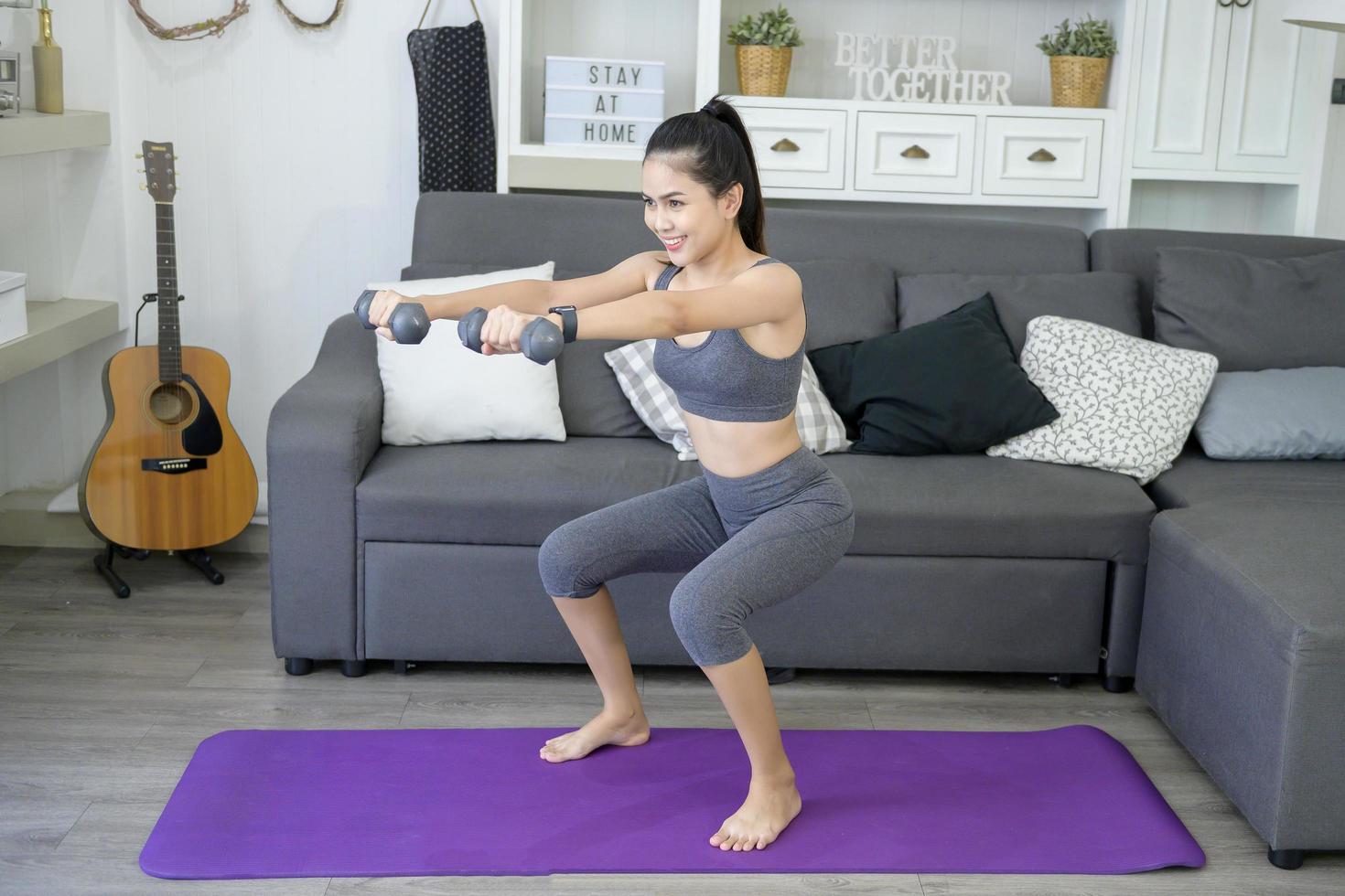 hermosa joven en ropa deportiva haciendo ejercicio con campanas en casa foto