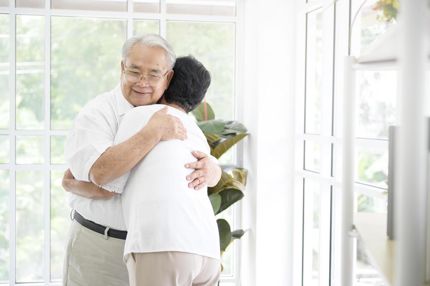 A senior elderly couple are hugging in home photo