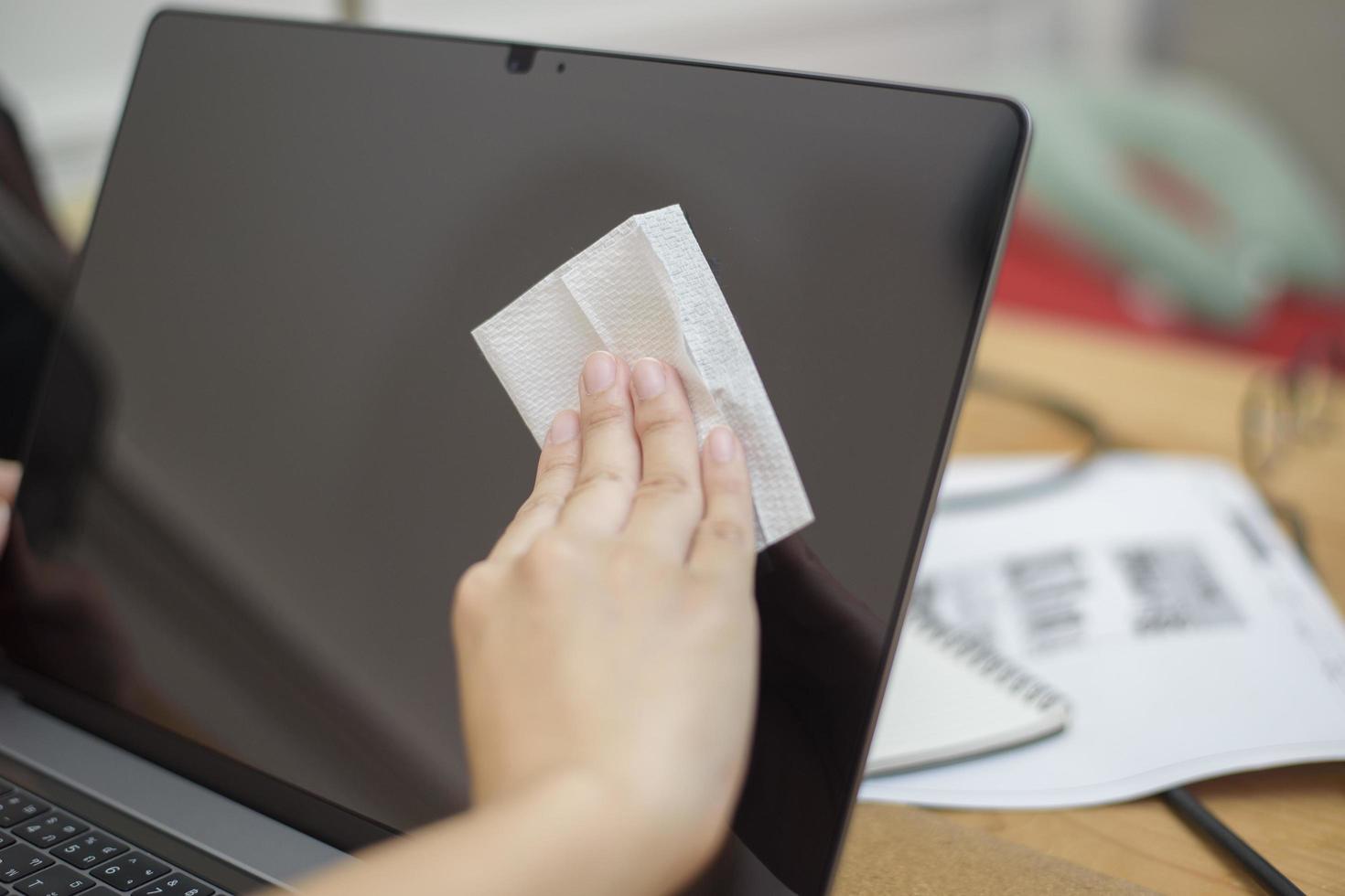 la mujer está limpiando la computadora portátil con spray de alcohol foto