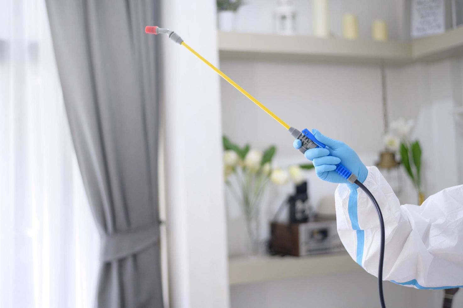 un personal médico con traje de ppe está usando spray desinfectante en la sala de estar, protección covid-19, concepto de desinfección. foto