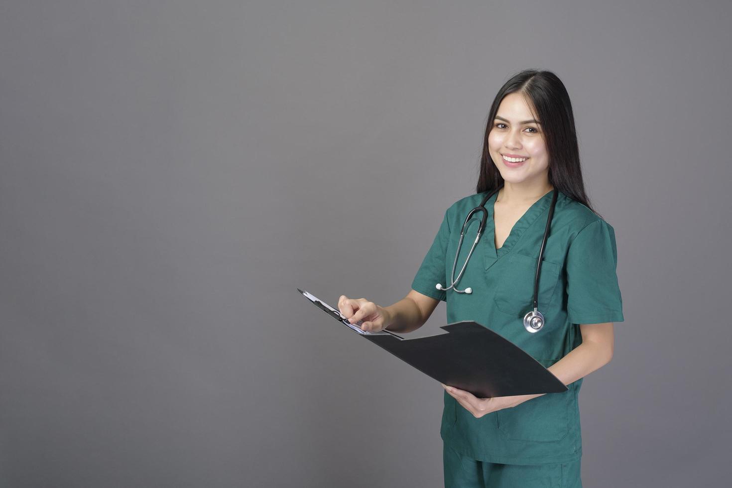 una joven doctora feliz y hermosa que lleva un uniforme verde tiene documentos foto