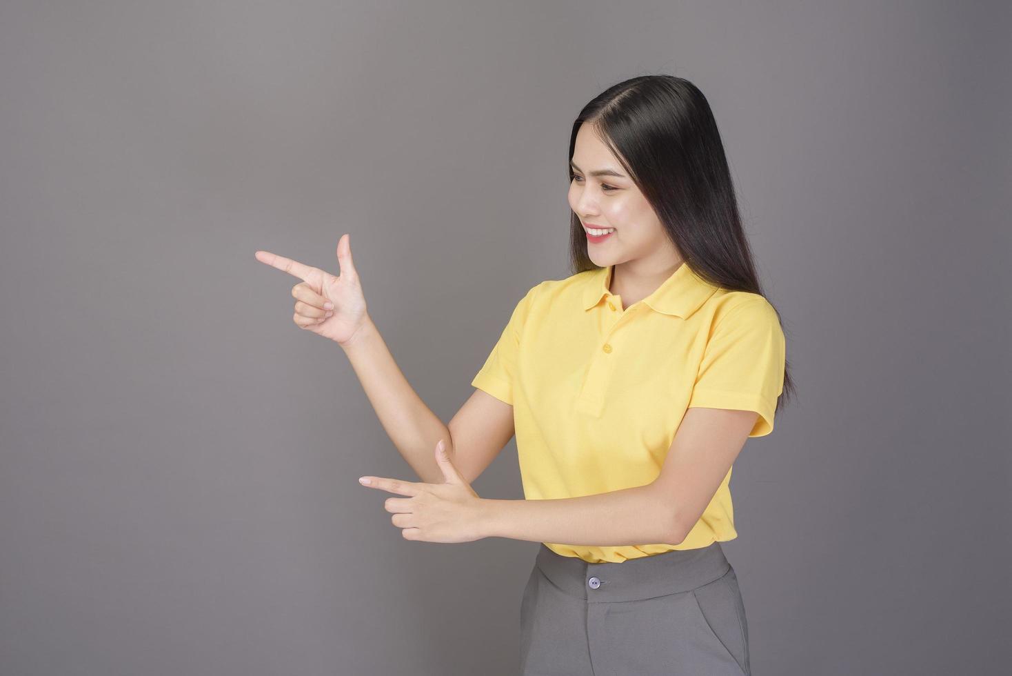 young confident beautiful woman wearing yellow shirt is on grey background studio photo