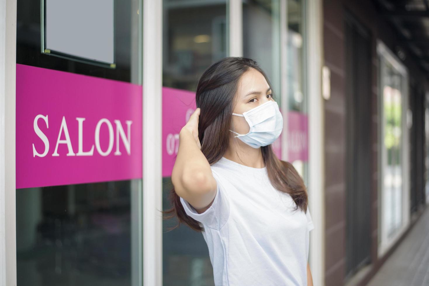 a young woman is wearing face mask for protection covid-19 standing in front of Salon shop, salon safety concept photo