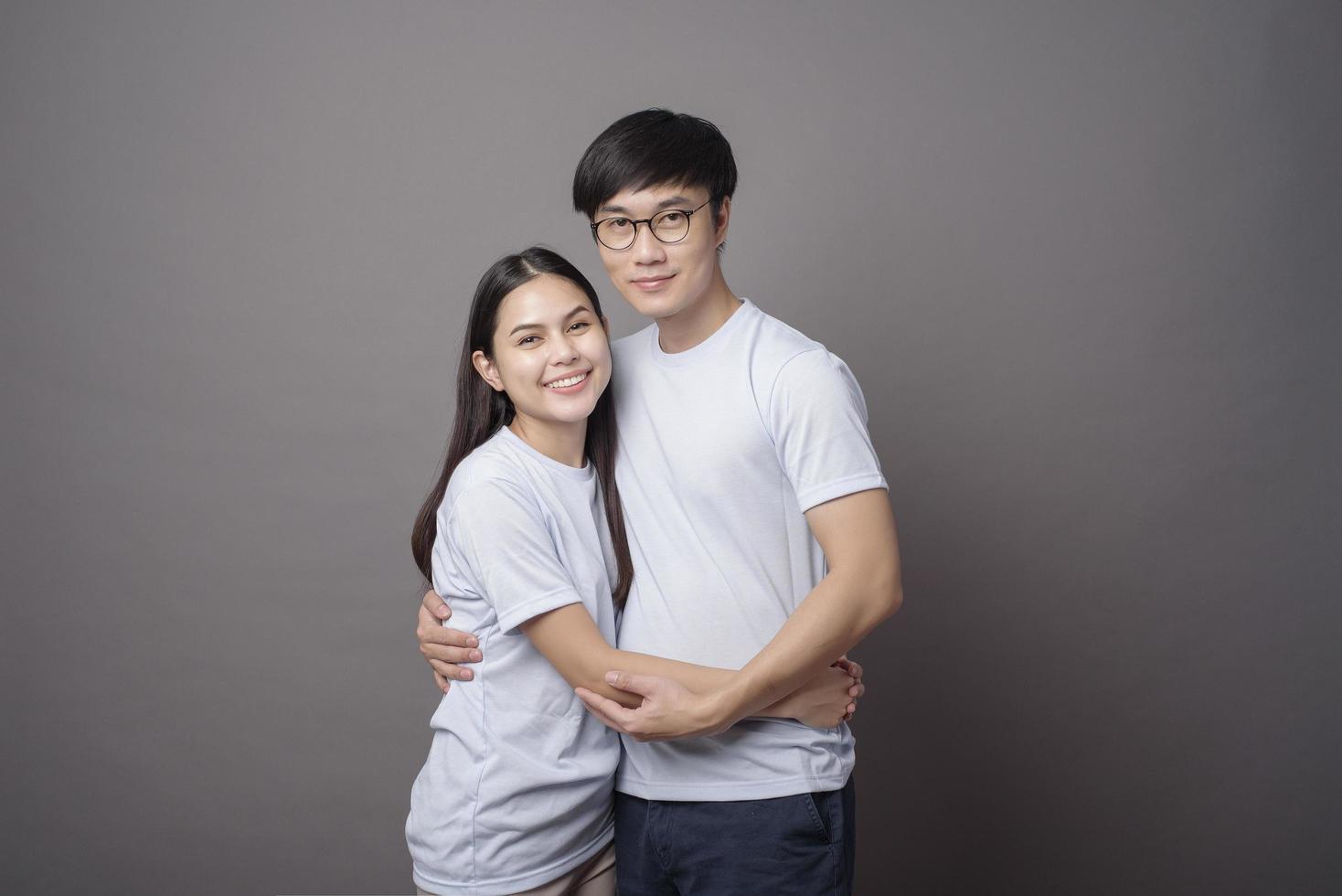 a portriat of a happy couple wearing blue shirt is hugging each other in grey background studio photo