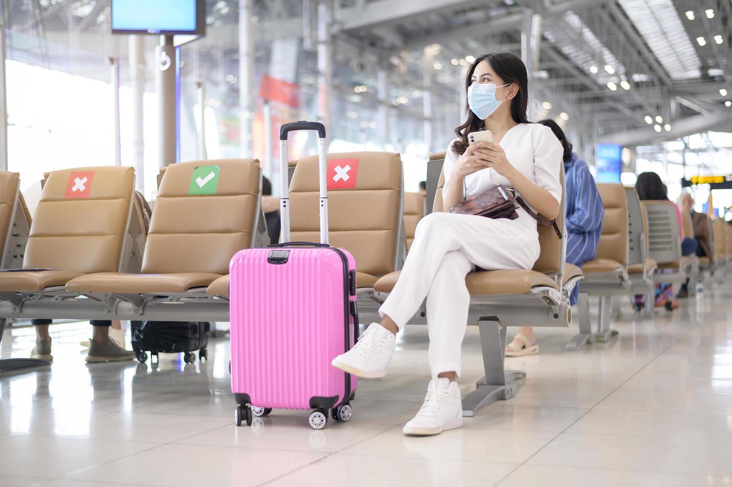 una mujer viajera lleva una máscara protectora en el aeropuerto internacional, viaja bajo la pandemia de covid-19, viajes de seguridad, protocolo de distanciamiento social, nuevo concepto de viaje normal foto