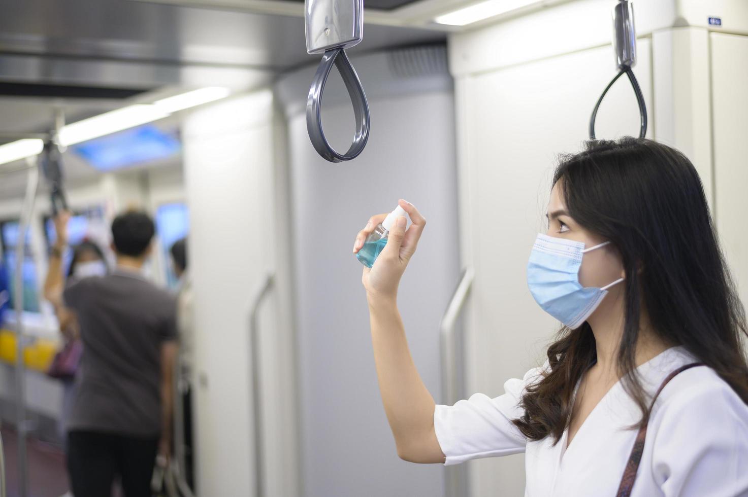 una mujer joven que usa una máscara protectora en el metro está usando  alcohol para lavarse