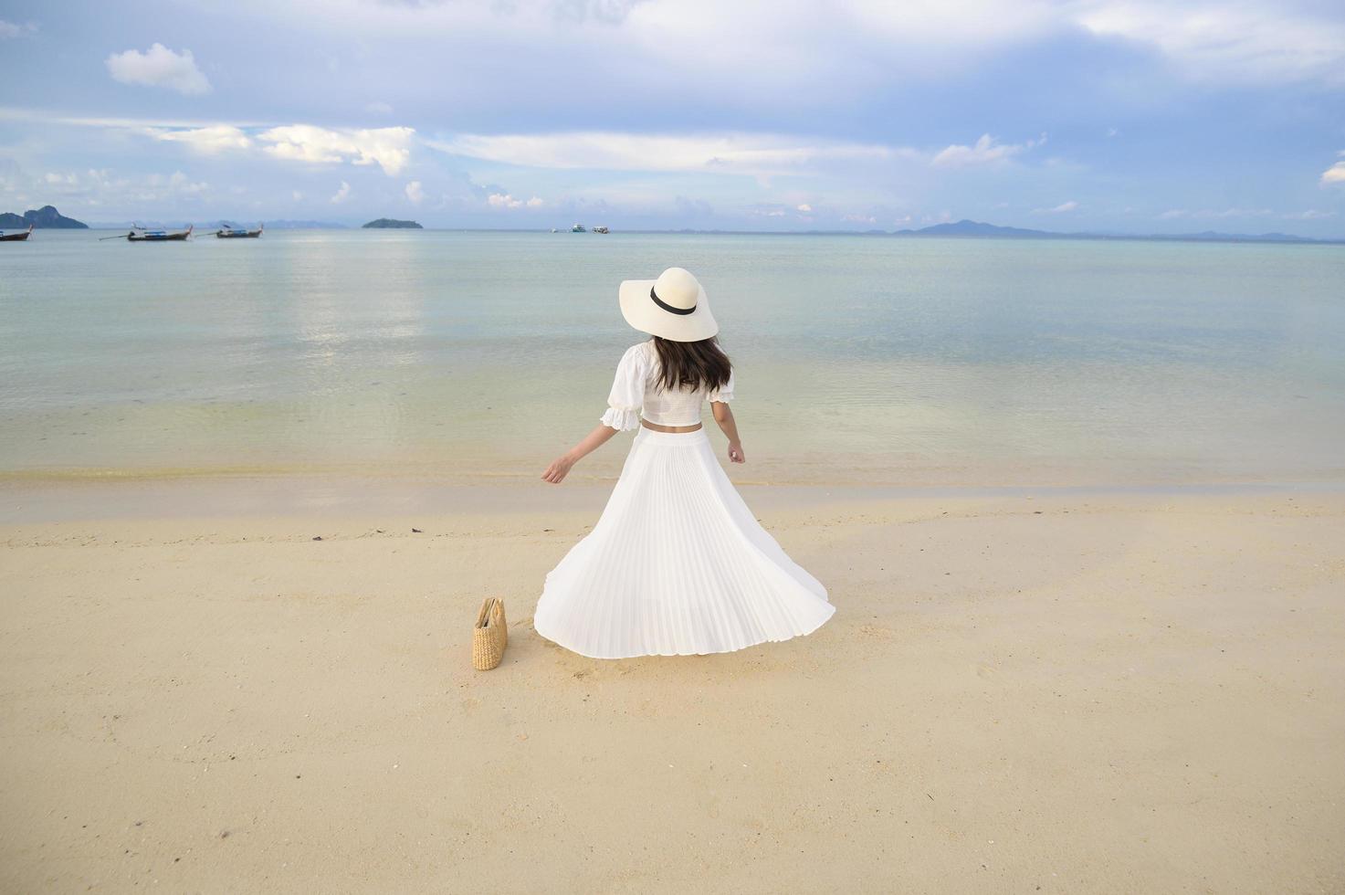 una hermosa mujer feliz con vestido blanco disfrutando y relajándose en el concepto de playa, verano y vacaciones foto