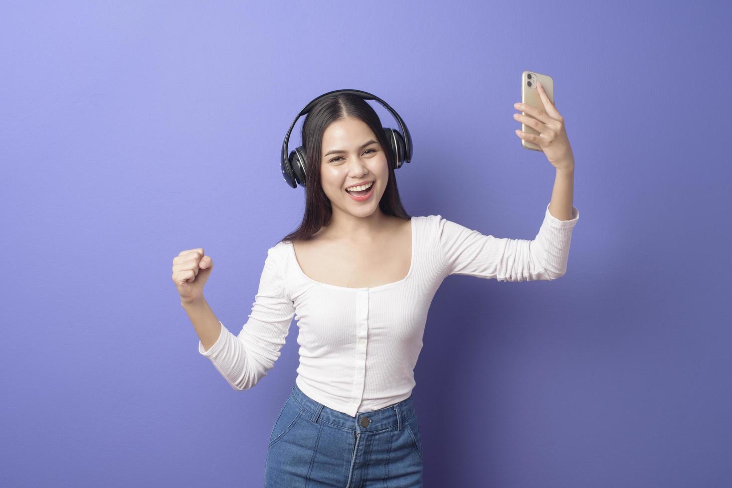 mujer joven está escuchando música con fondo morado foto