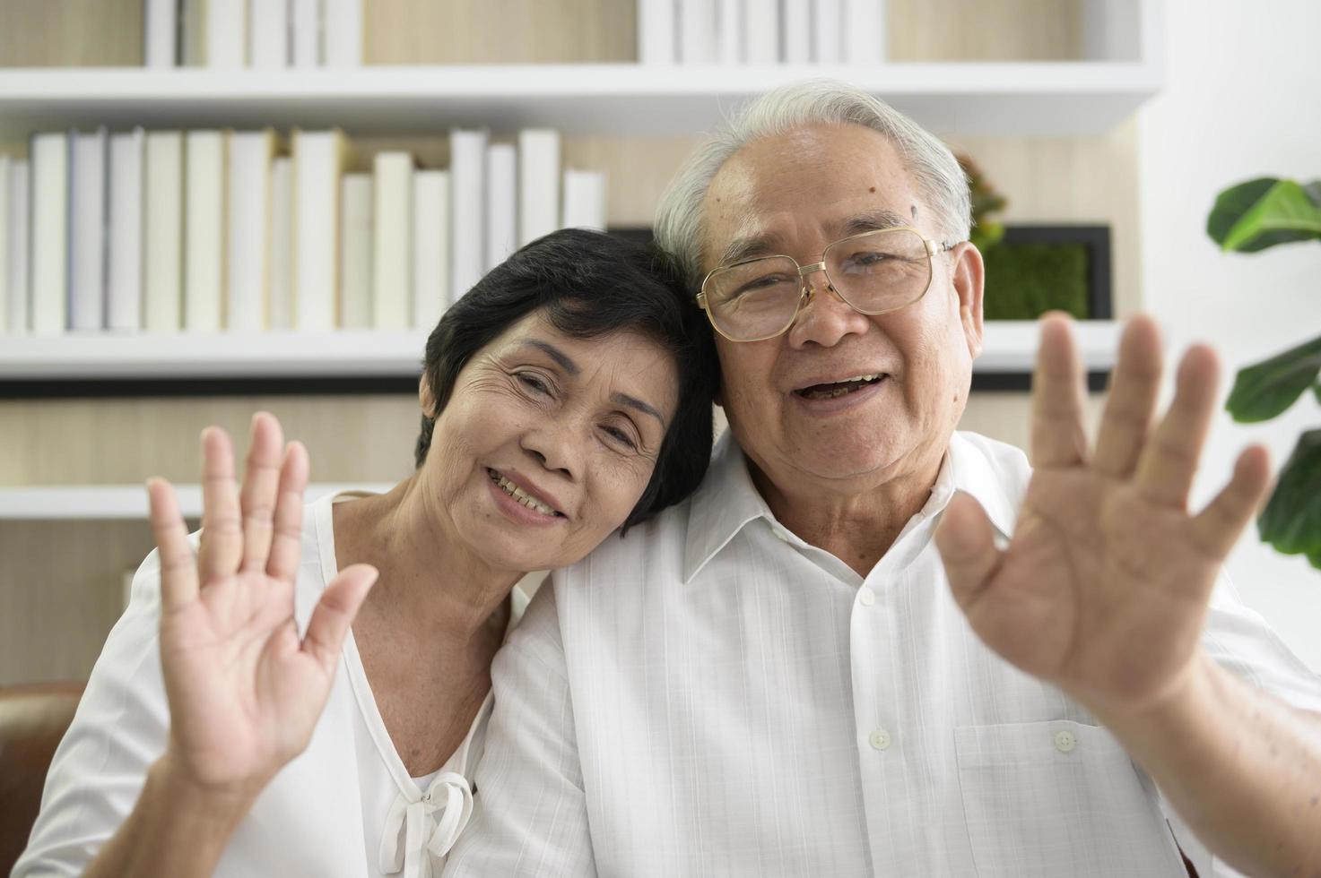 un anciano feliz asiático está haciendo videollamadas, se relaja en casa, sonríe abuelos jubilados sanos, concepto de tecnología de abuelos mayores foto