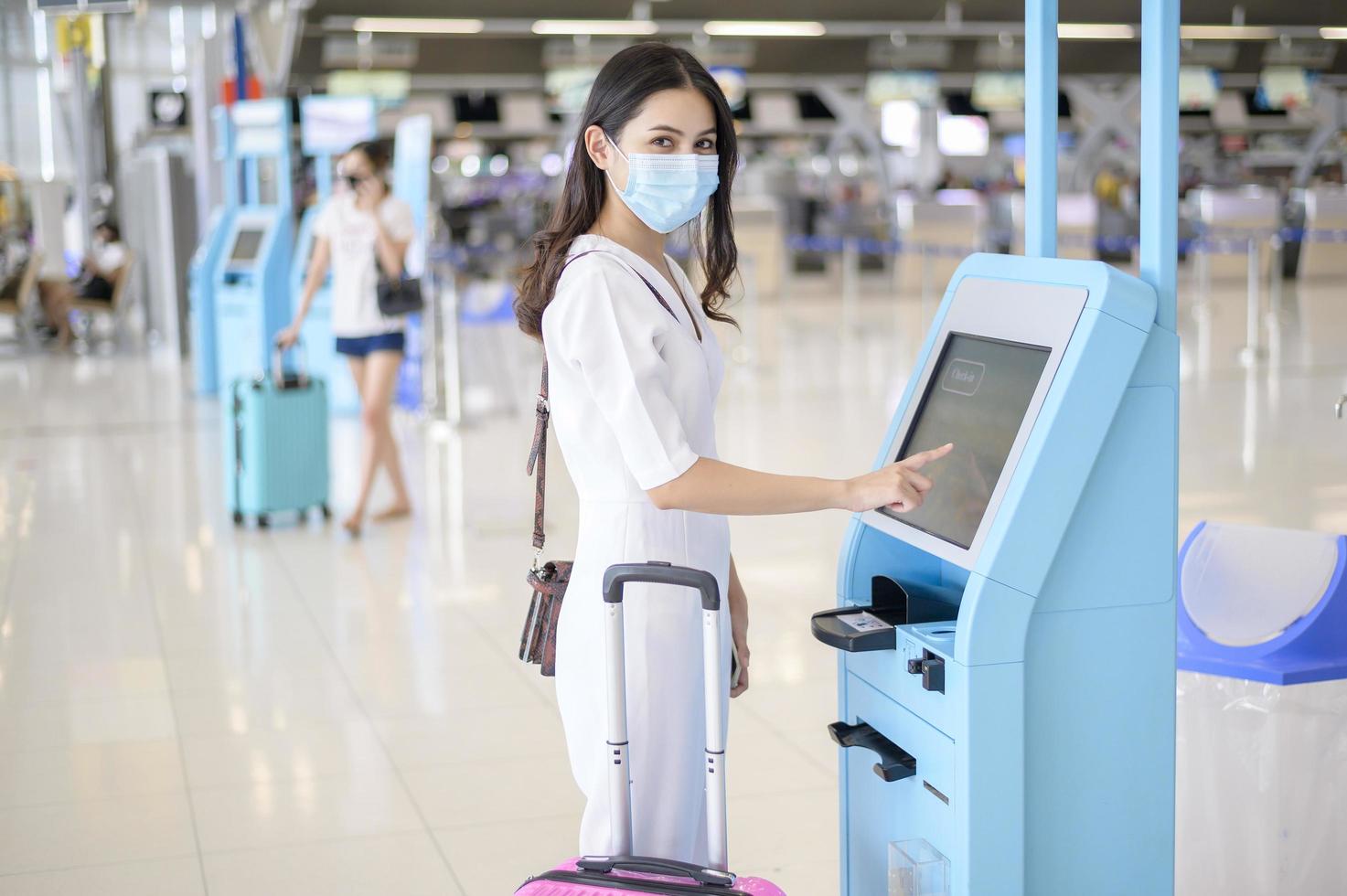 una mujer viajera lleva una máscara protectora en el aeropuerto internacional, viaja bajo la pandemia de covid-19, viajes de seguridad, protocolo de distanciamiento social, nuevo concepto de viaje normal foto