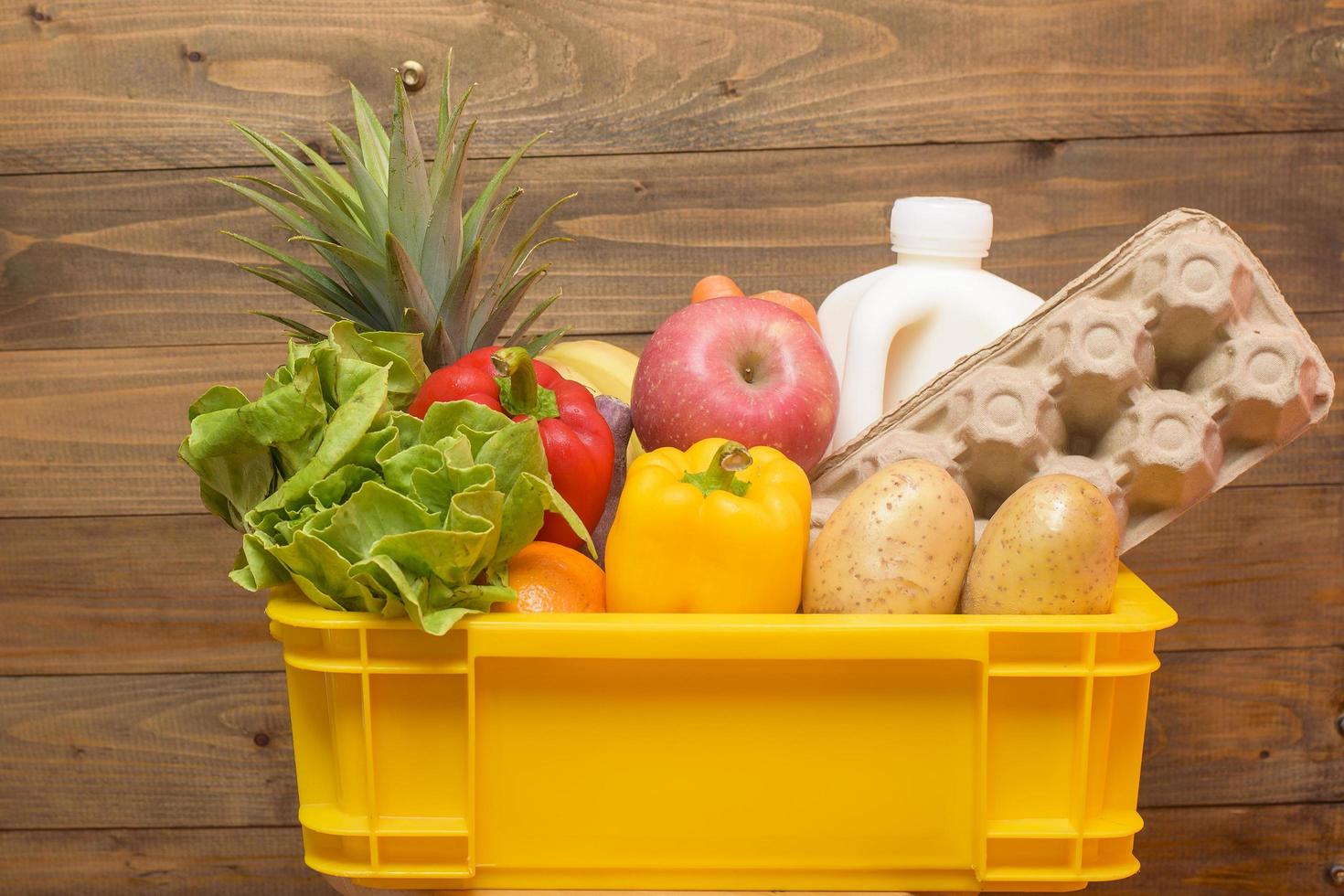 conjunto de entrega de alimentos crudos en caja de plástico sobre fondo de madera foto