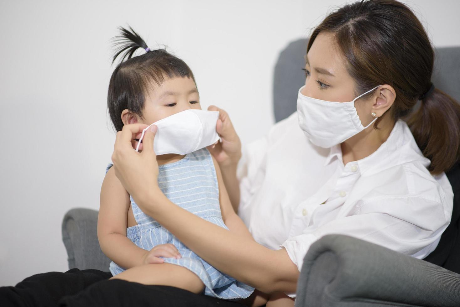 Mom and daughter are wearing protective mask , safety in home , covid-19 protection , healthy at home concept photo