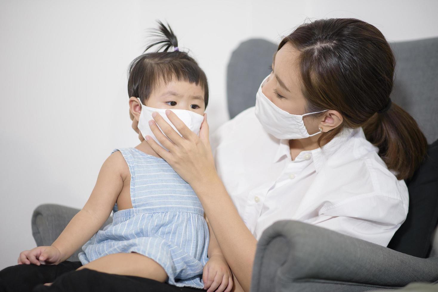 Mom and daughter are wearing protective mask , safety in home , covid-19 protection , healthy at home concept photo