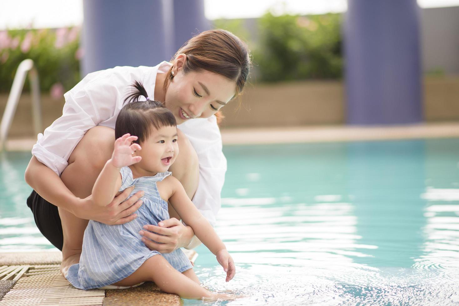 A Happy Asian mother and daughter are enjoy swimming in pool , lifestyle, parenthood, family concept photo