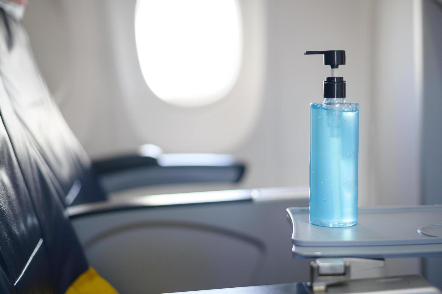 el desinfectante de gel de alcohol está en la mesa de la bandeja en el avión para los pasajeros durante el vuelo foto