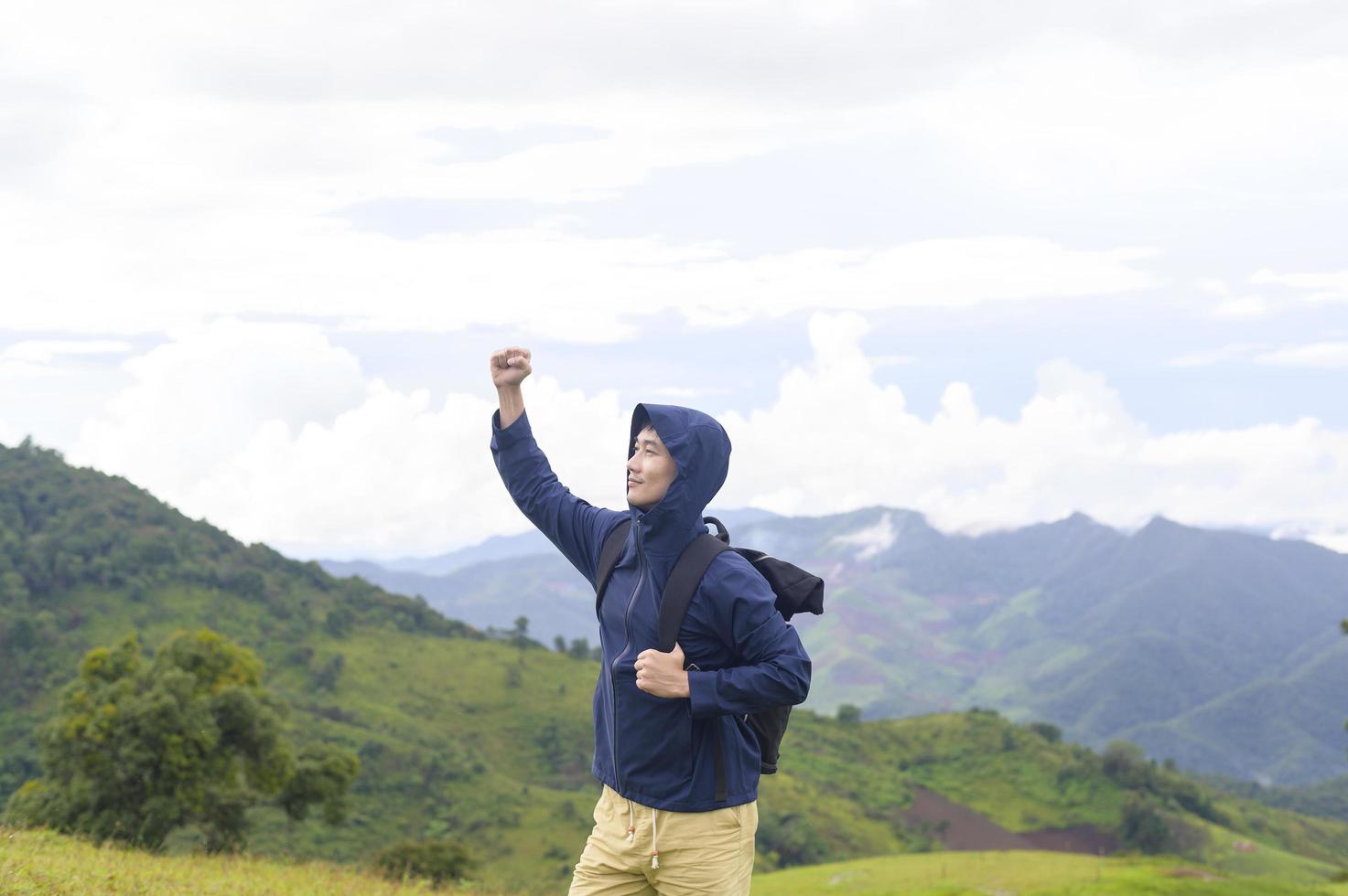 Traveling man enjoying and relaxing over beautiful green mountain view in rain season, Tropical climate. photo