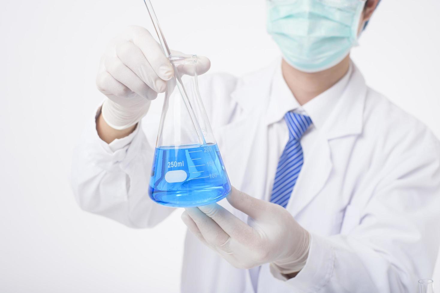 el primer plano del científico está probando e investigando algún químico líquido azul en un fondo blanco aislado de laboratorio. foto