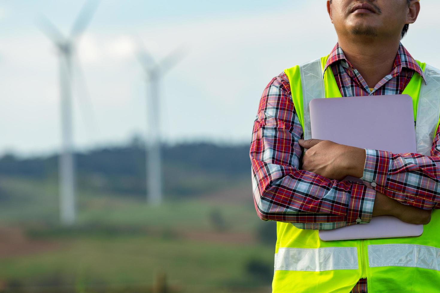 Engineering man standing holding laptop looking wind turbines clean energy project for produce electricity smart service of engineer clean energy. photo