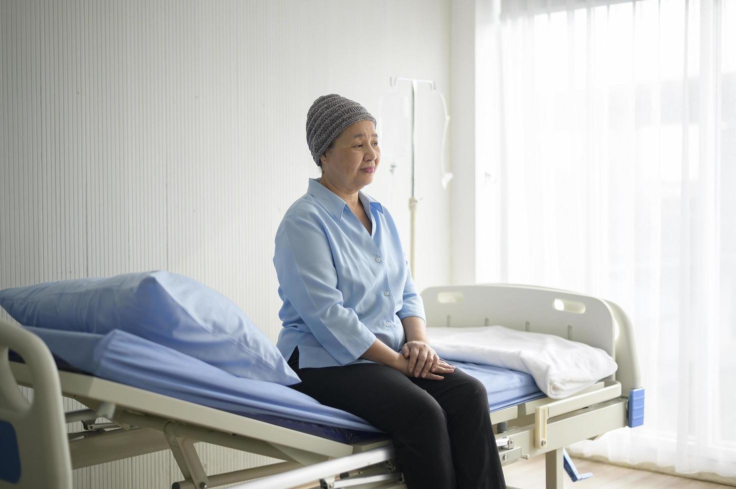 Depressed and hopeless Asian cancer patient woman wearing head scarf in hospital. photo