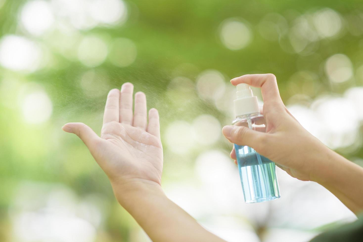 Close up hand with alcohol sanitizer spray outdoor photo