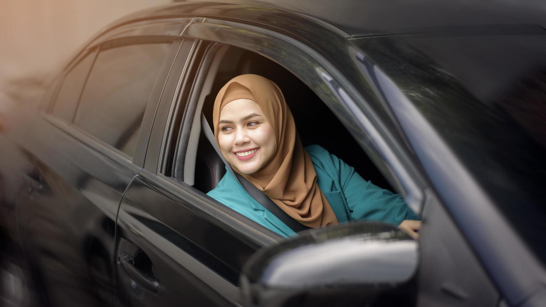hermosa mujer de negocios con hiyab está sonriendo en su auto foto