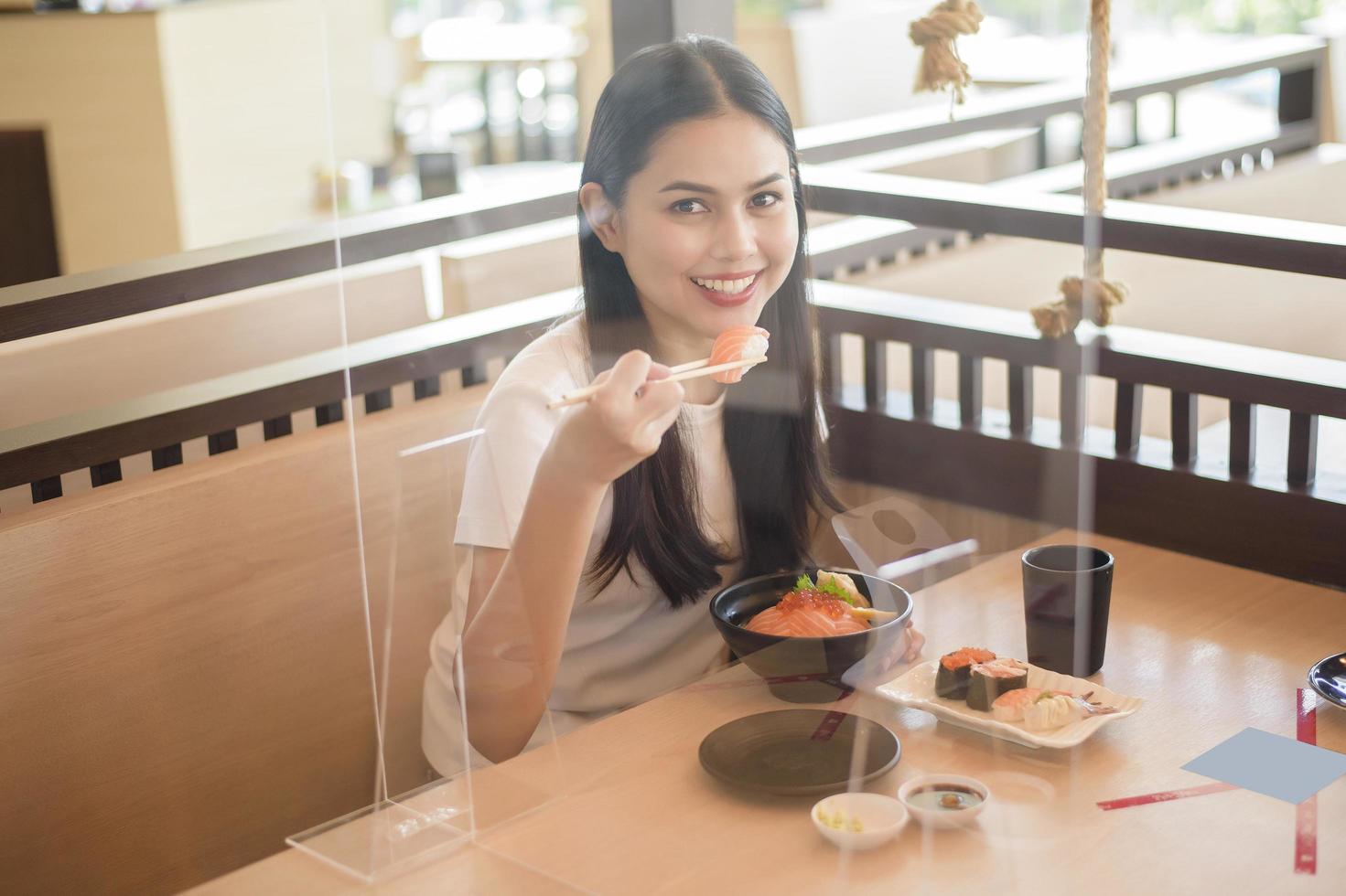 la mujer está comiendo en un restaurante con protocolo de distanciamiento social mientras se encierra la ciudad debido a la pandemia del coronavirus foto