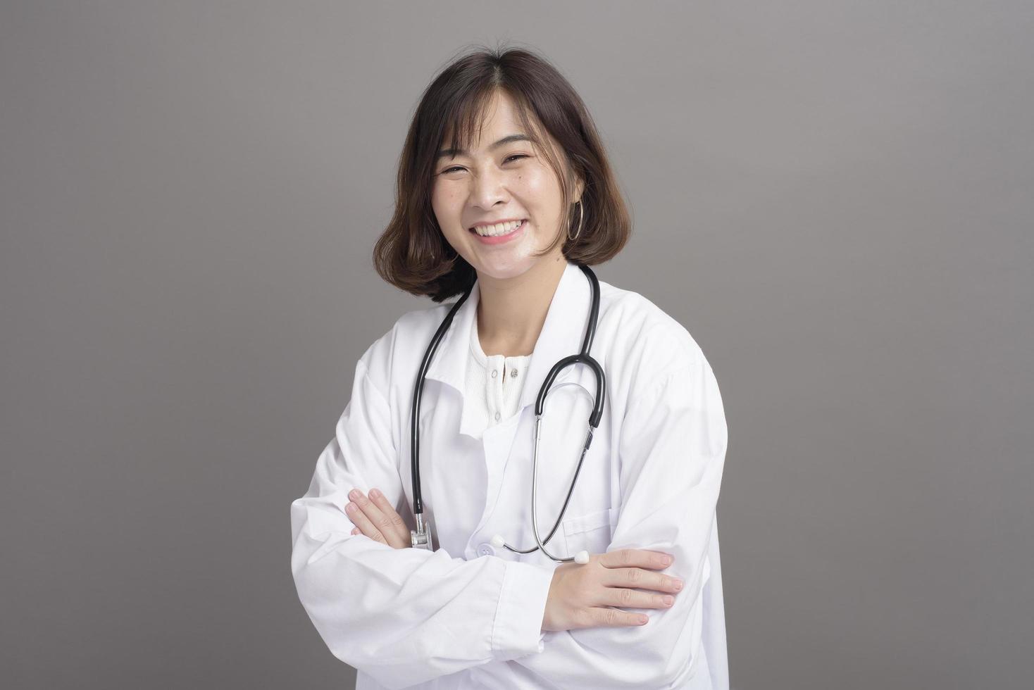 Portrait of young confident woman doctor isolated over grey background studio photo