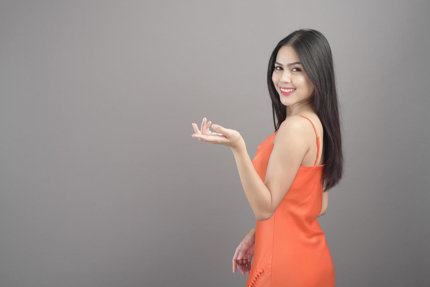 Fashion portrait of beautiful woman wearing orange dress isolated over gray background studio photo