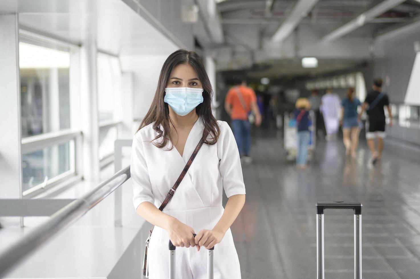 una mujer viajera lleva una máscara protectora en el aeropuerto internacional, viaja bajo la pandemia de covid-19, viajes de seguridad, protocolo de distanciamiento social, nuevo concepto de viaje normal foto