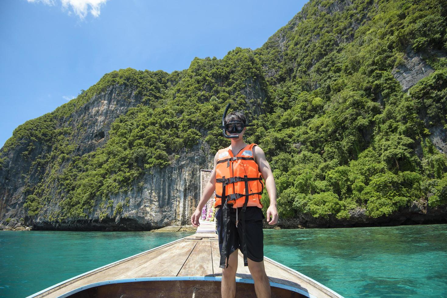 un hombre activo en un bote de cola larga tradicional tailandés está listo para bucear y bucear, islas phi phi, tailandia foto