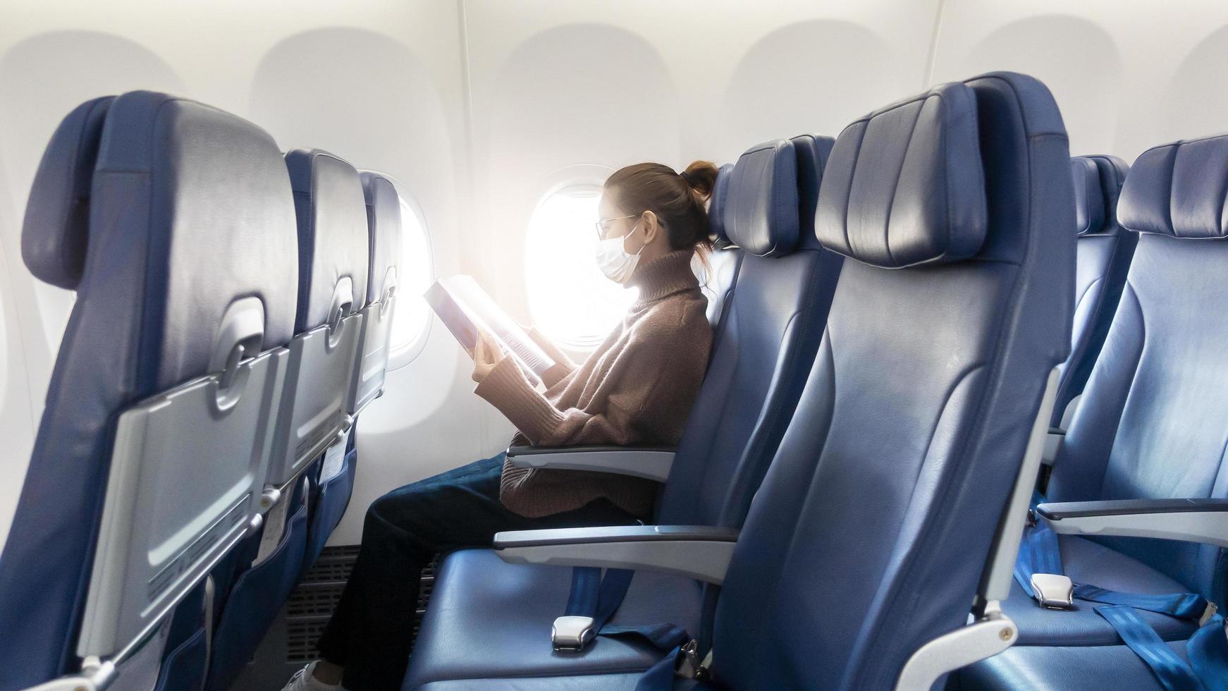 A young woman wearing face mask is traveling on airplane , New normal travel after covid-19 pandemic concept photo