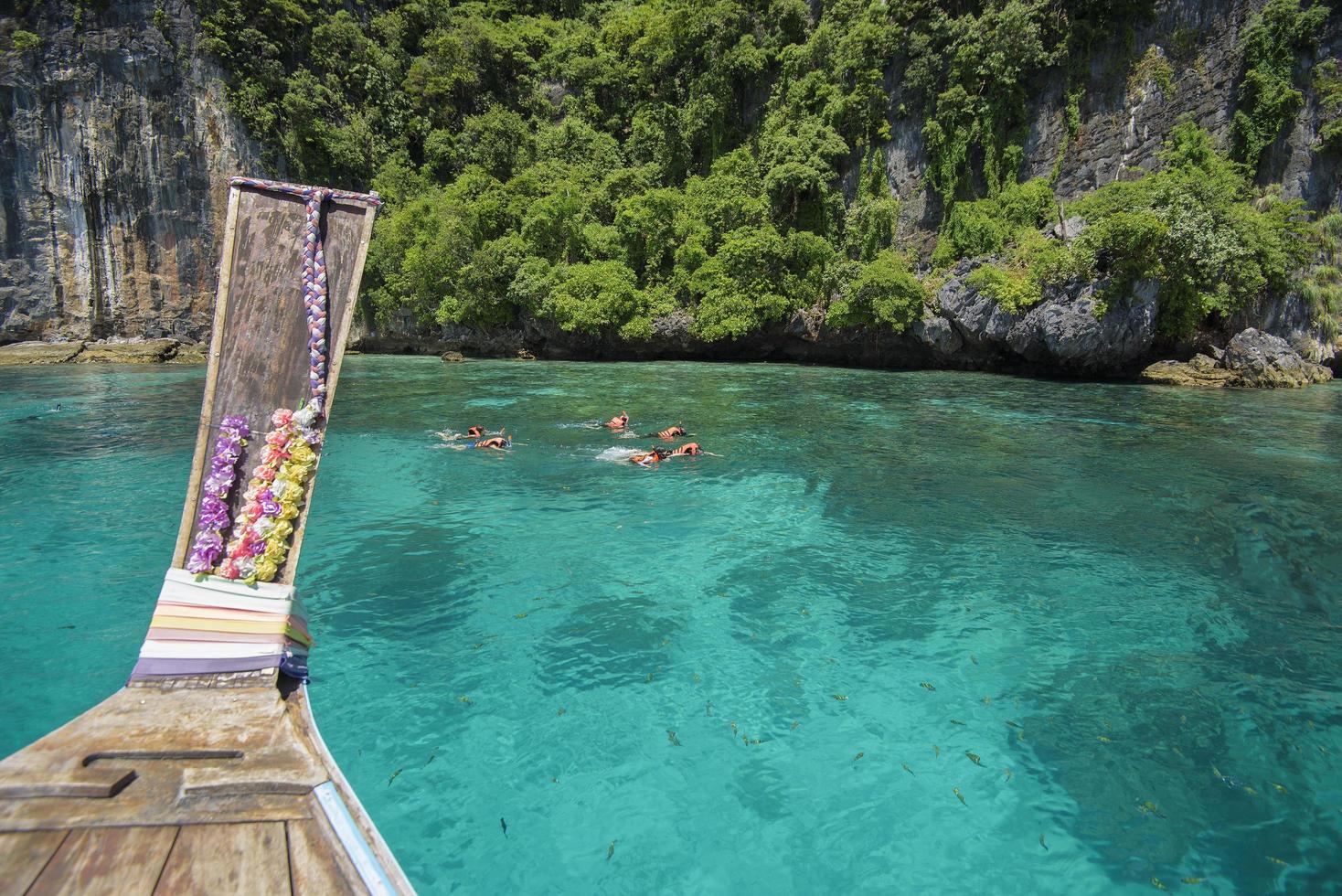 view from thai traditional longtail Boat while tourists snorkeling and diving in the ocean, Phi phi Islands, Thailand photo