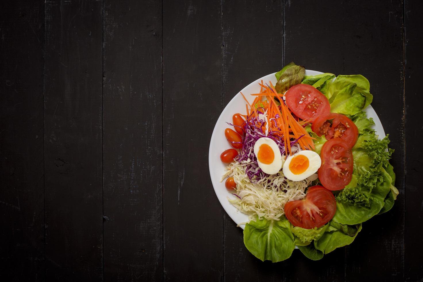 ensalada de verduras sobre fondo de madera negra foto