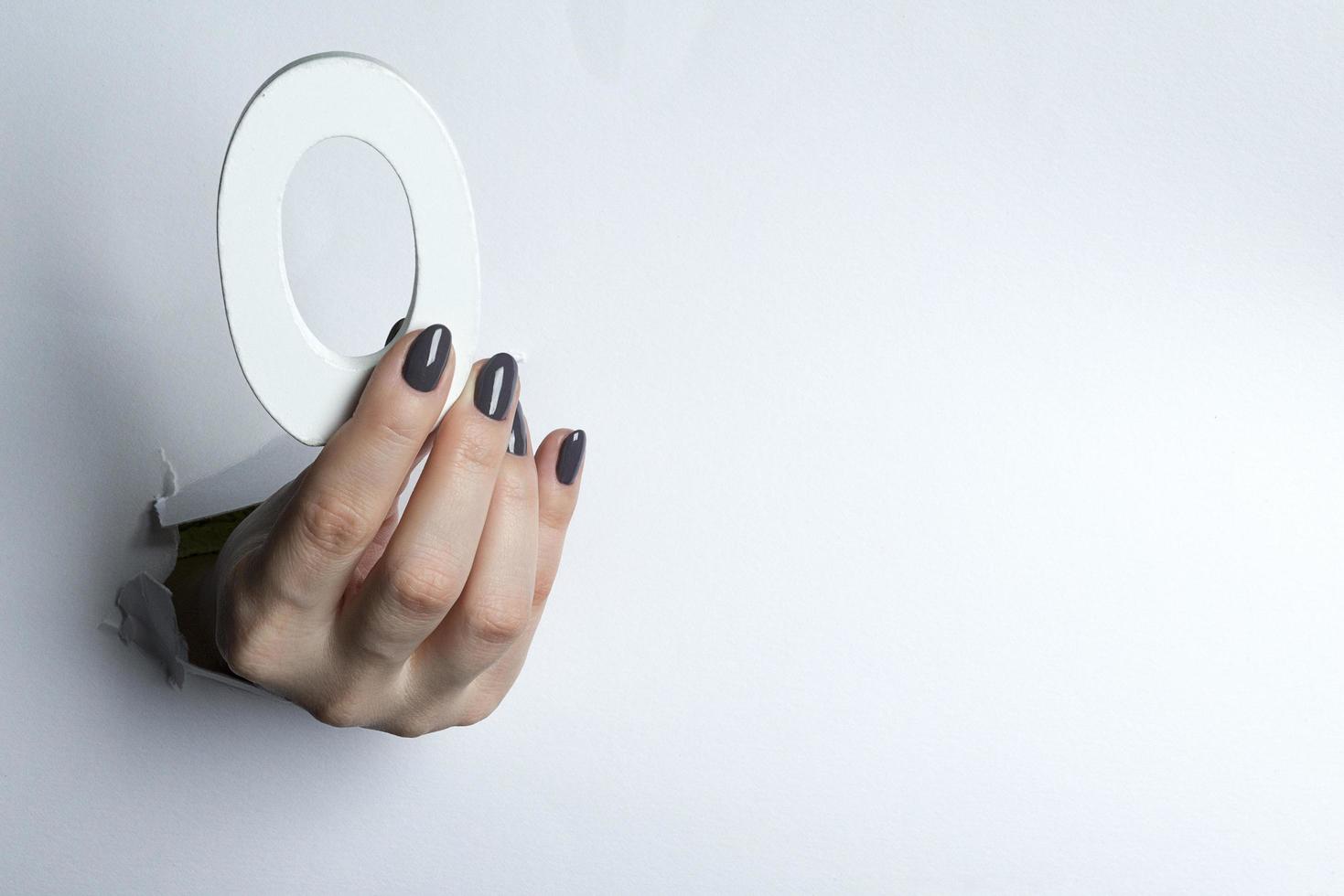 Female hand holding up the number 0 against a white . photo
