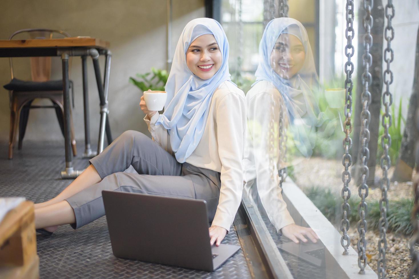 Muslim woman with hijab is working with laptop computer in coffee shop photo