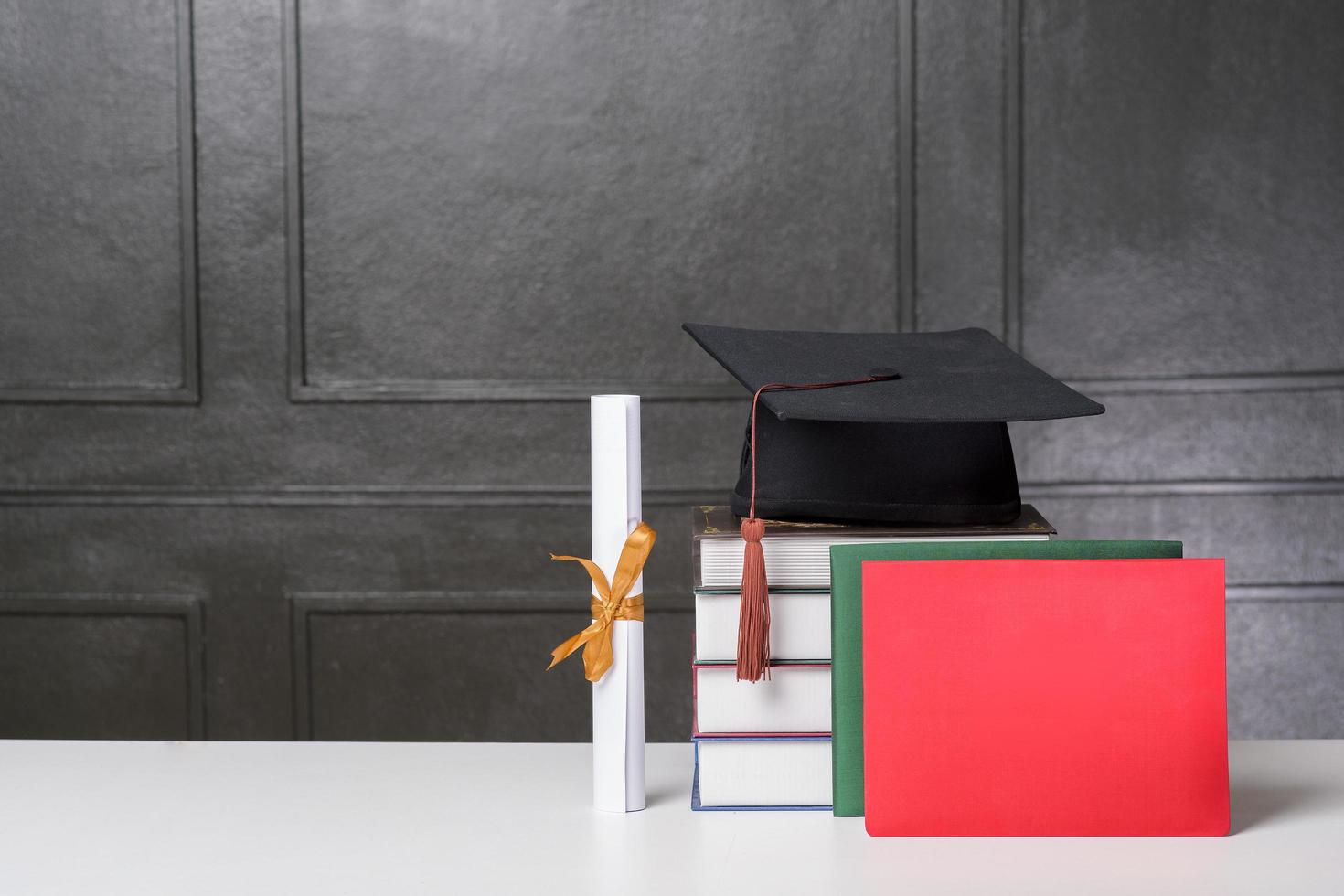 gorra de graduación con libros en escritorio blanco, antecedentes educativos foto