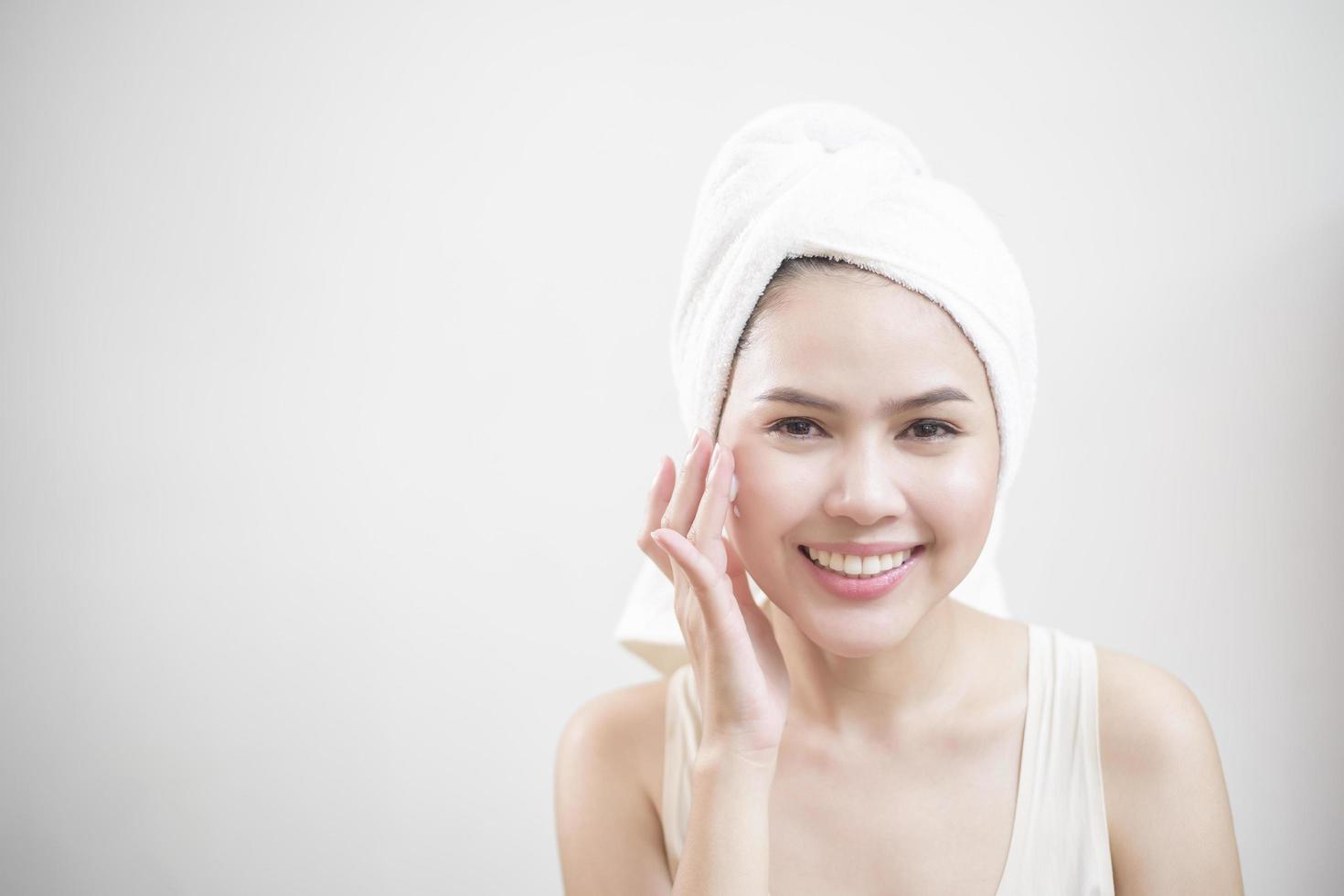 A woman is applying cream on her face photo