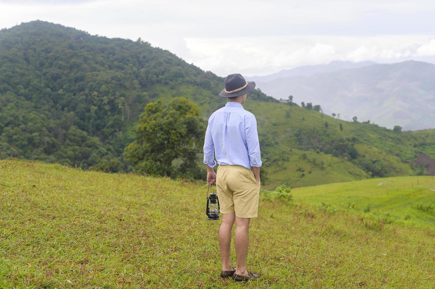 hombre viajero disfrutando y relajándose sobre la hermosa vista verde de la montaña en temporada de lluvia, clima tropical. foto