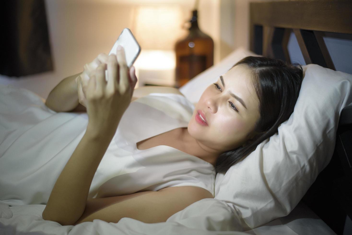 Woman is feeling eye pain when using smart phone at night photo