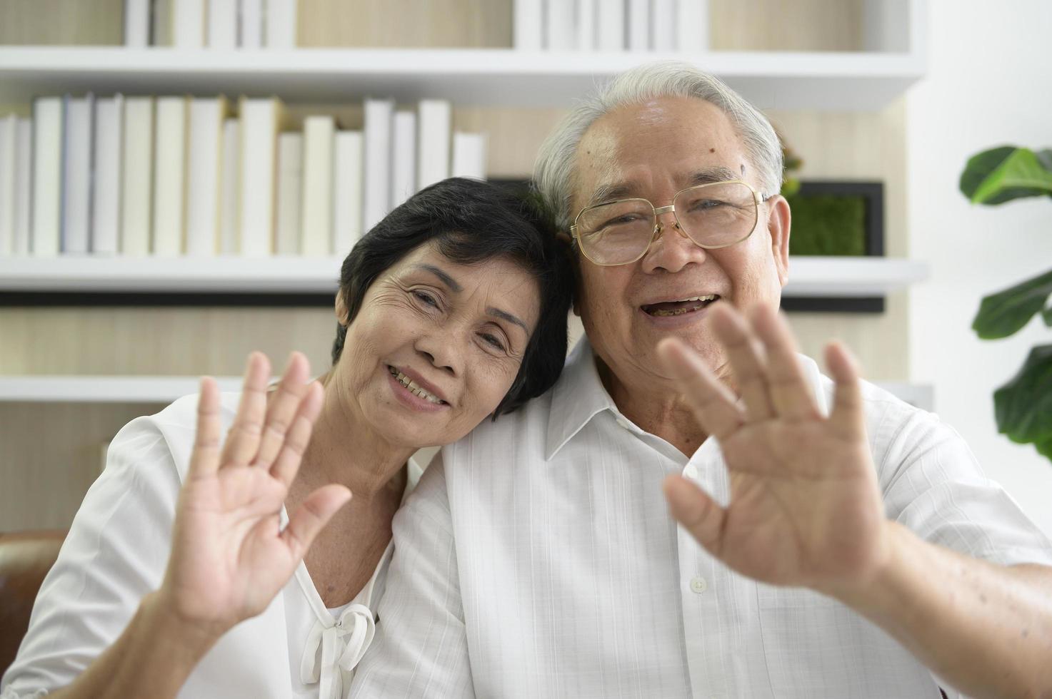 un anciano feliz asiático está haciendo videollamadas, se relaja en casa, sonríe abuelos jubilados sanos, concepto de tecnología de abuelos mayores foto