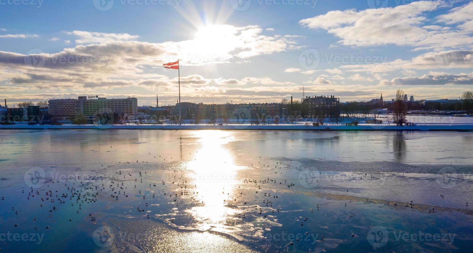 Beautiful view of the frozen river with sea gulls sitting on the ice by the old town of Riga in Latvia. photo