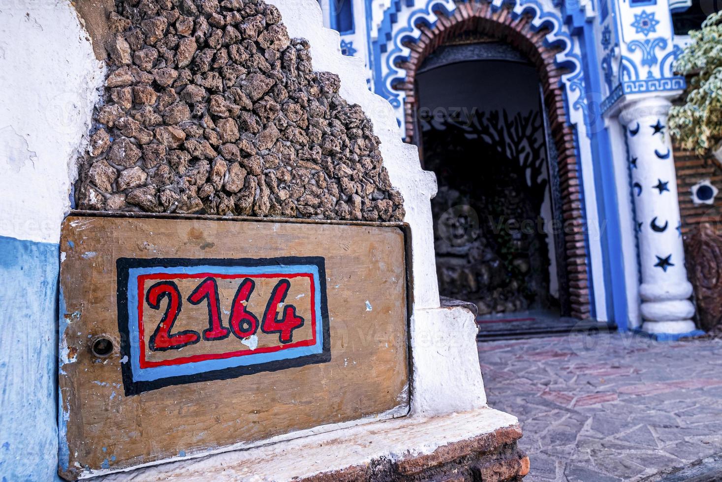 Footpath with house number on wooden plank, abstract ornate through arched entrance photo